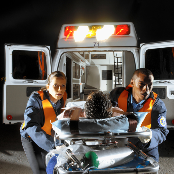 Two young paramedics wheeling a male patient on a stretcher out of an ambulance