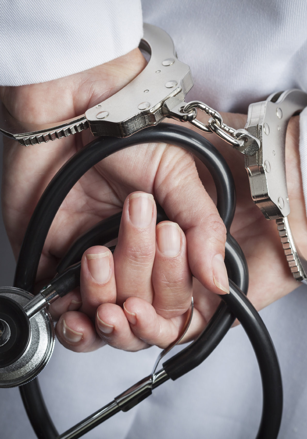 Female Doctor or Nurse In Handcuffs and Lab Coat Holding Stethoscope.