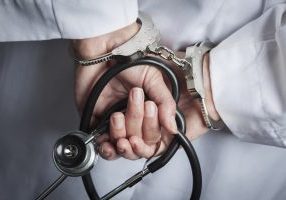 Female Doctor or Nurse In Handcuffs and Lab Coat Holding Stethoscope.