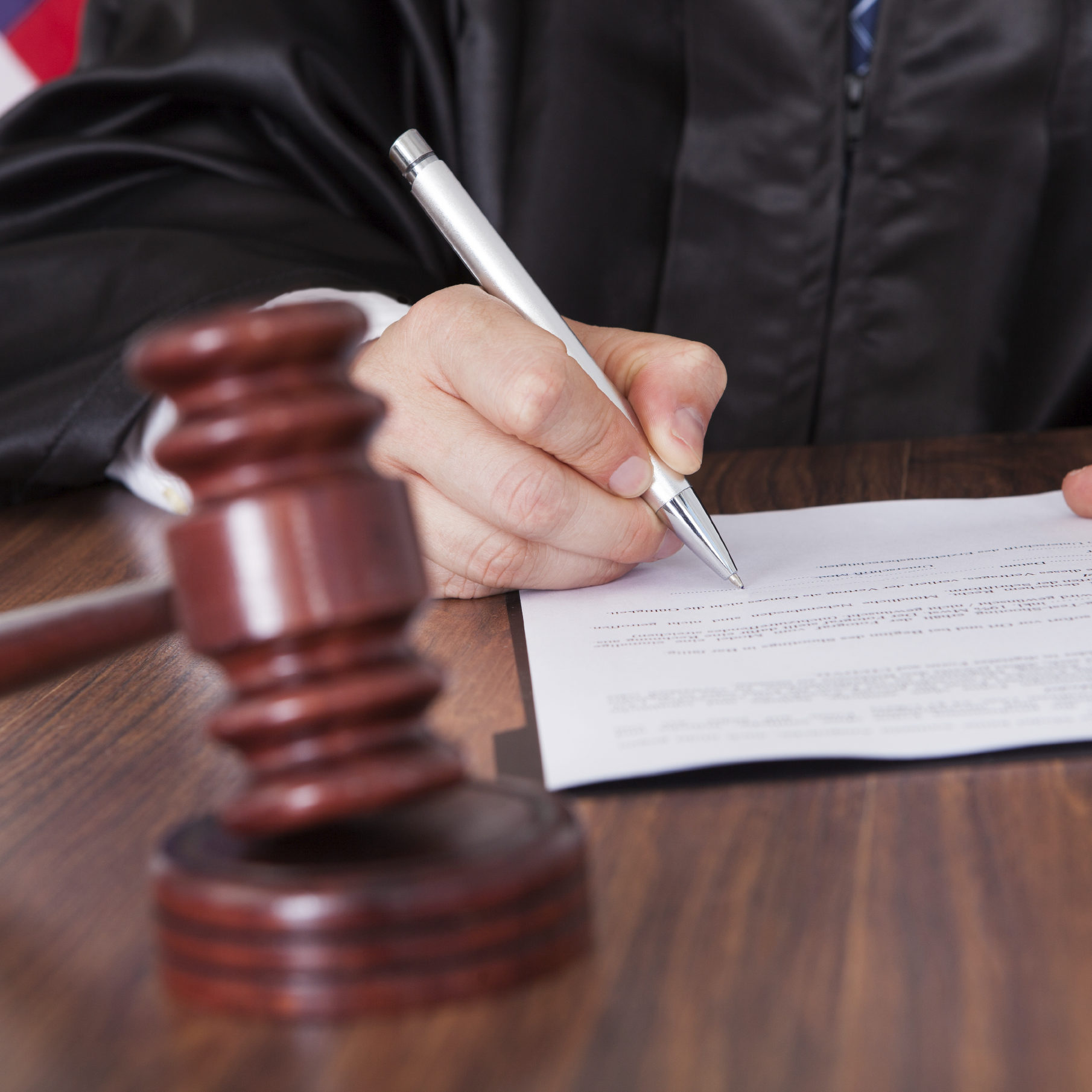 Close-up Of Male Judge Writing On Paper In Courtroom